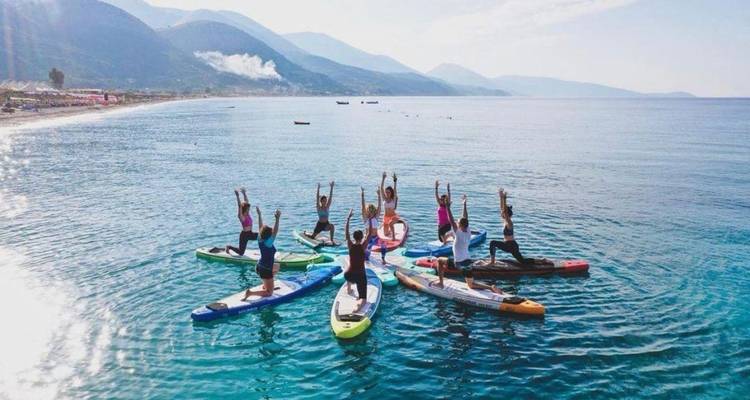 Des gens pratiquant le yoga sur des planches à pagaie dans un océan calme.