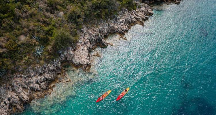 Deux kayaks près d'une côte rocheuse dans une eau claire.