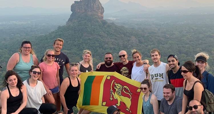 Groupe de personnes avec un drapeau devant une grande formation rocheuse.