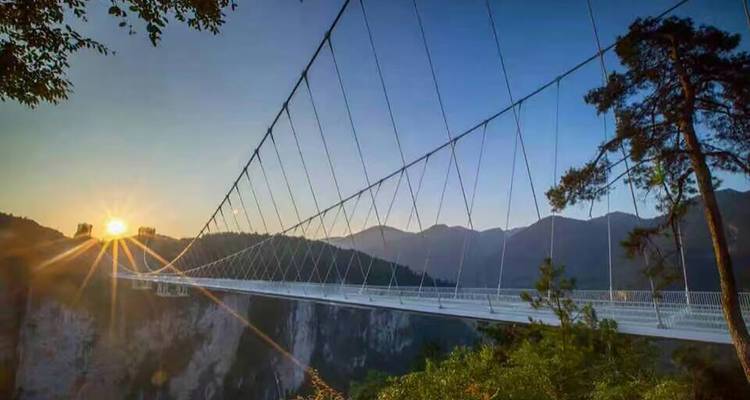 Puente colgante sobre un cañón con un amanecer