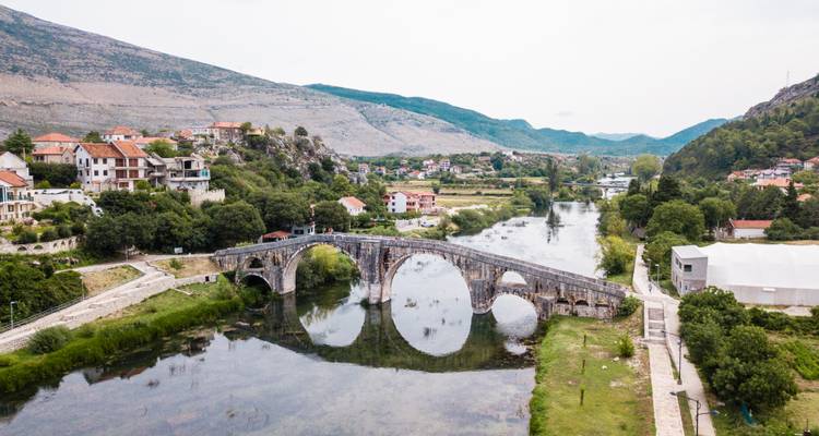 Eine historische Steinbrücke über einem Fluss mit üppig grüner Umgebung.
