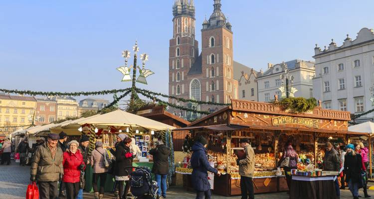 Un bullicioso mercado navideño con puestos y una iglesia histórica en Cracovia.