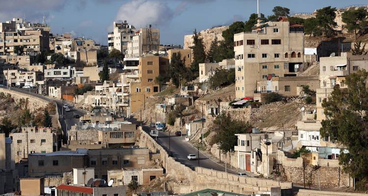 Hillside Jordanian town with terraced houses and a winding road climbing the slope.