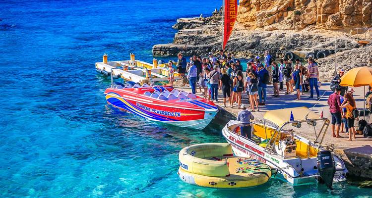 Tourists gathered by speedboats in clear blue water