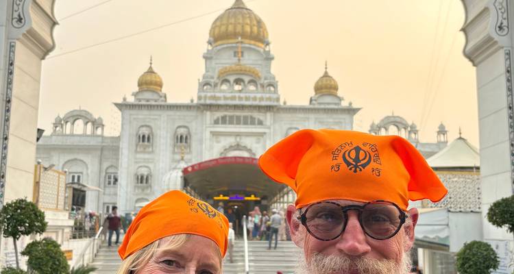 Deux personnes debout devant un temple sikh portant des turbans orange.