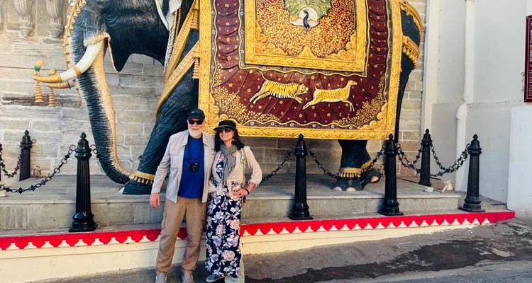 Zwei Touristen stehen vor einem detaillierten gemalten Elefantenwandgemälde an einer Palastwand in Rajasthan.