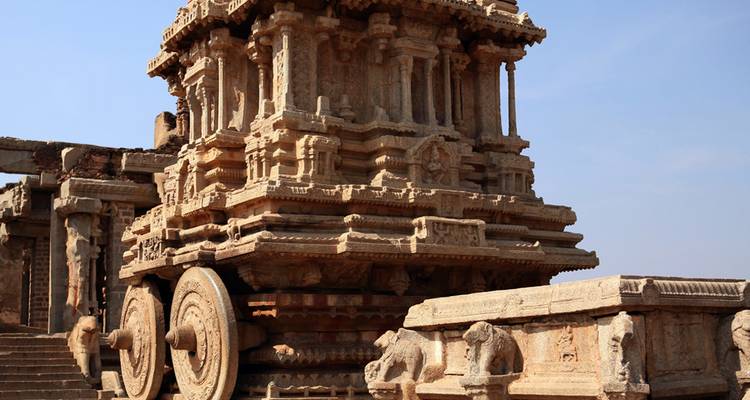 De stenen wagen van Hampi staat onder een helder blauwe lucht en toont fraaie Vijayanagara-snijwerk.