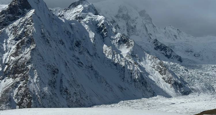 Snow-covered mountain landscape under a cloudy sky.