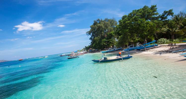Tropical beach with clear water and boats.