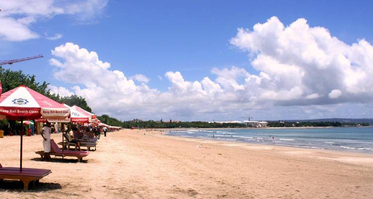 Sandy beach with umbrellas and a clear blue sky.