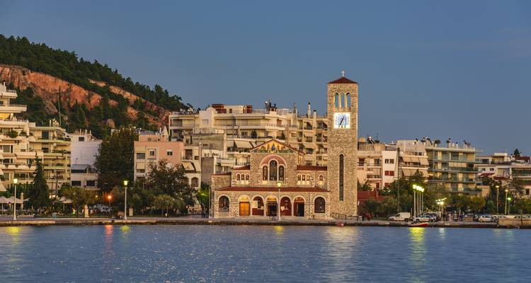 Ein Blick vom Wasser auf einen Uhrenturm und eine Kirche in der Dämmerung.