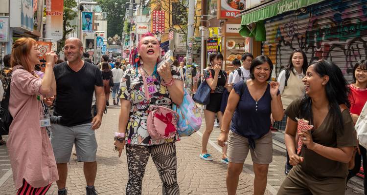 Una guía colorida entretiene a un grupo de turistas en la animada calle Takeshita de Tokio, llena de tiendas.