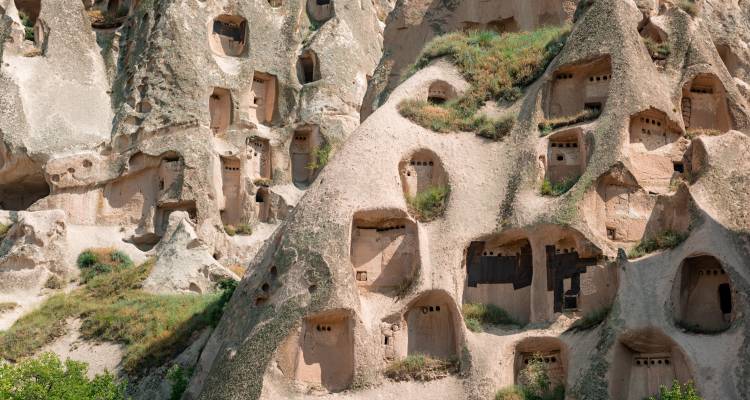 Ancient rock-cut cave dwellings in a rocky hillside.