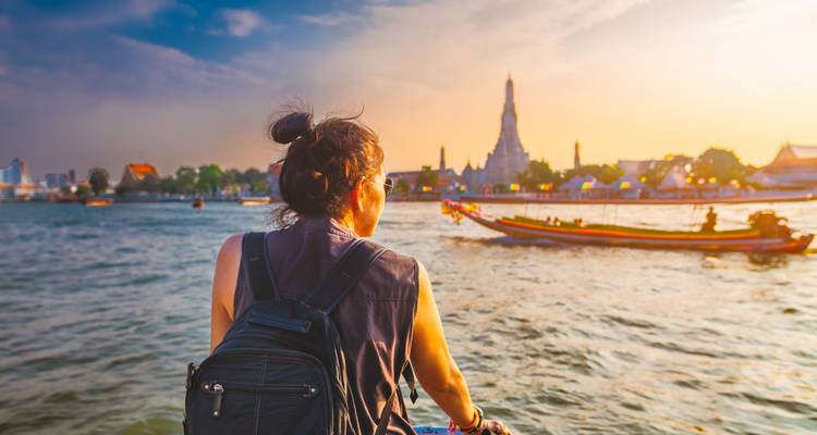 Femme lors d'une promenade en bateau avec vue sur le Wat Arun au coucher du soleil.