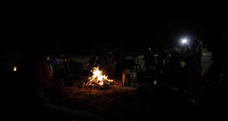 Feu de camp avec des gens assis autour la nuit.