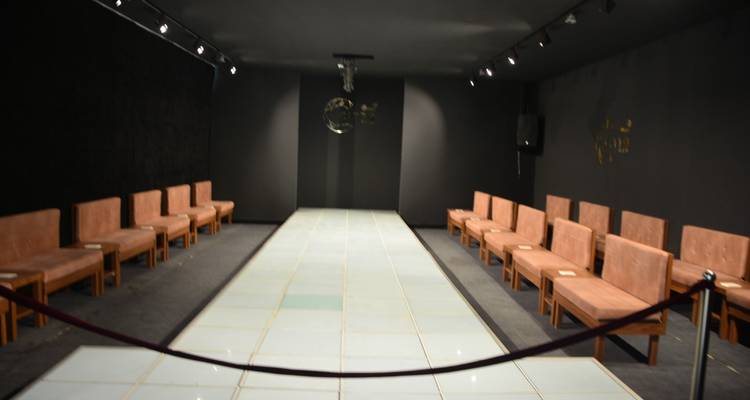 Leerer Flur mit Reihen brauner Sitze unter schwachem Licht.