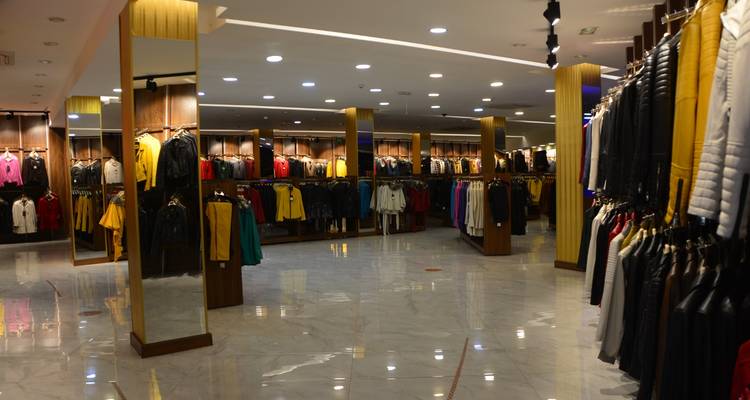 Innenraum eines gut beleuchteten Bekleidungsgeschäfts mit verschiedener ausgestellter Kleidung.