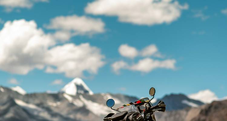 Gedeeltelijk zicht op een motorfiets met de Himalaya-bergen op de achtergrond.