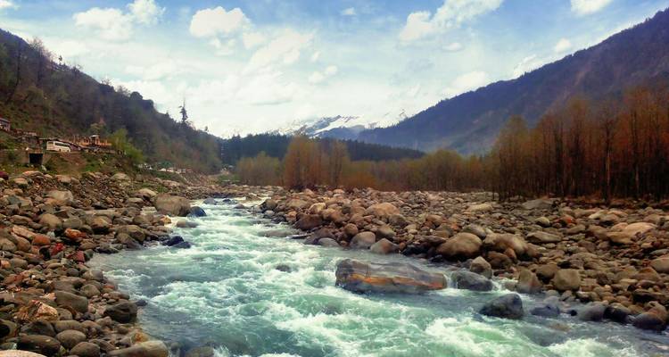 Een rivier die door een rotsachtig landschap stroomt met bergen op de achtergrond.