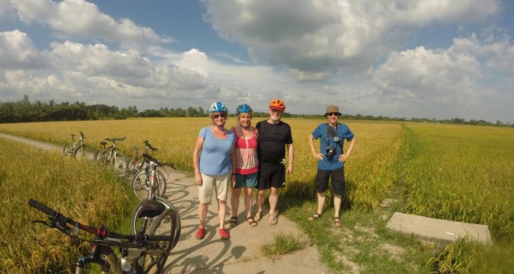 Quatre personnes qui posent dans une rizière avec des vélos.