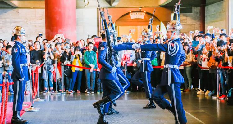 Relève de la garde cérémonielle avec des soldiers en uniformes bleus exécutant des exercices de fusil devant une grande foule à l'intérieur