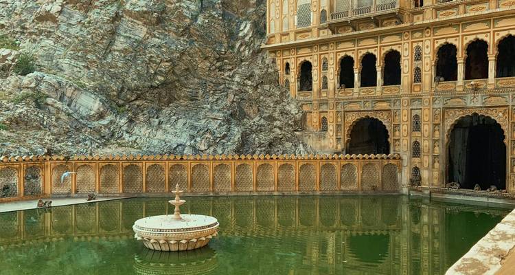 View of a historic temple with a fountain in the forefront.