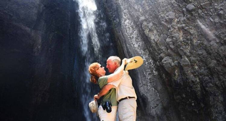 Paar umarmt sich vor einem großen Wasserfall.