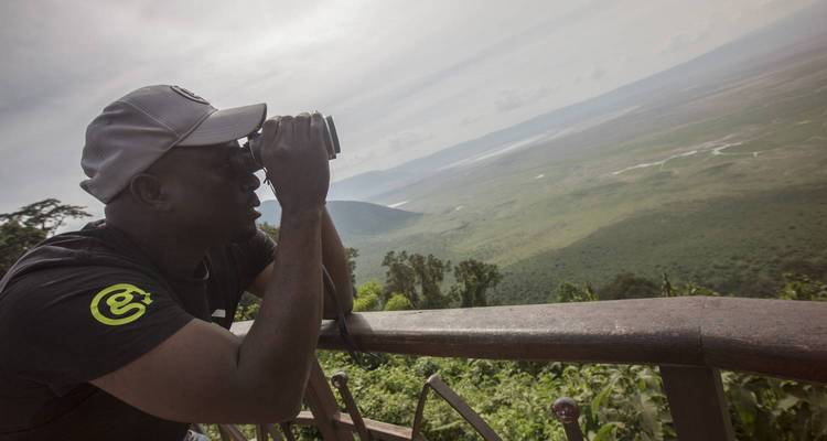 Person, die ein Fernglas benutzt, um eine Landschaft von einem Aussichtspunkt aus zu betrachten.
