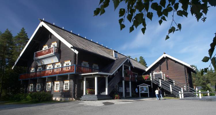 Traditionelles Holzgebäude in Finnland mit Menschen draußen.