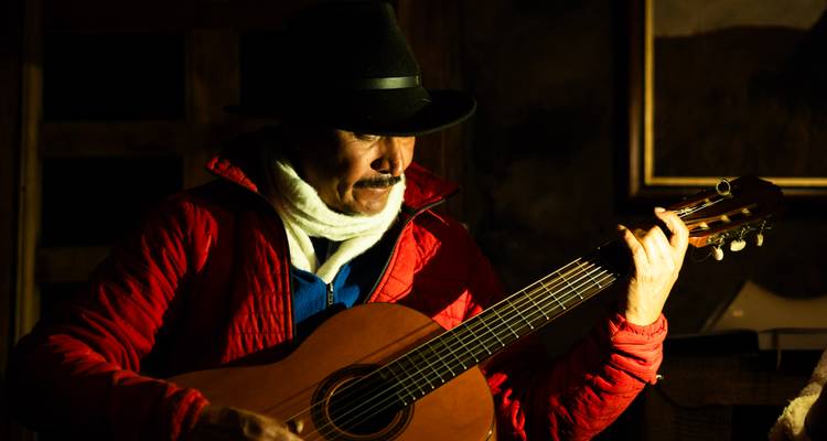 Ein Mann, der in schwachem Licht Gitarre spielt.