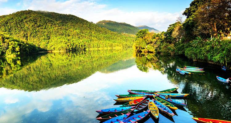 Kleurrijke boten op een serene meer omringd door weelderige groene heuvels.