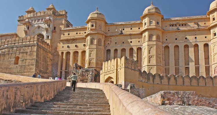 Een persoon die trappen beklimt naar een groot, historisch fort.