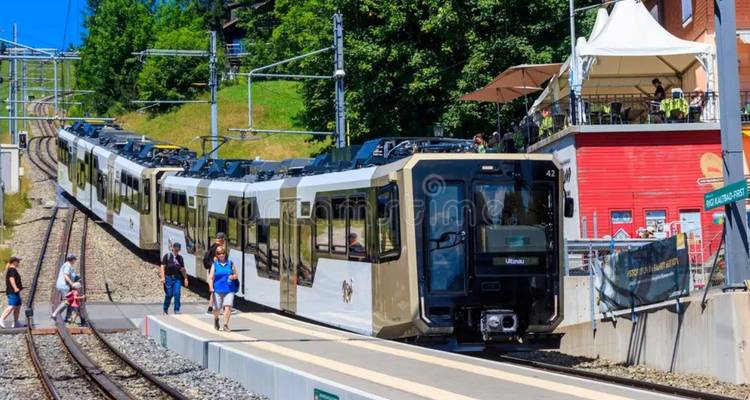 Train à crémaillère suisse à une gare de montagne avec des passagers en cours d'embarquement par une belle journée ensoleillée