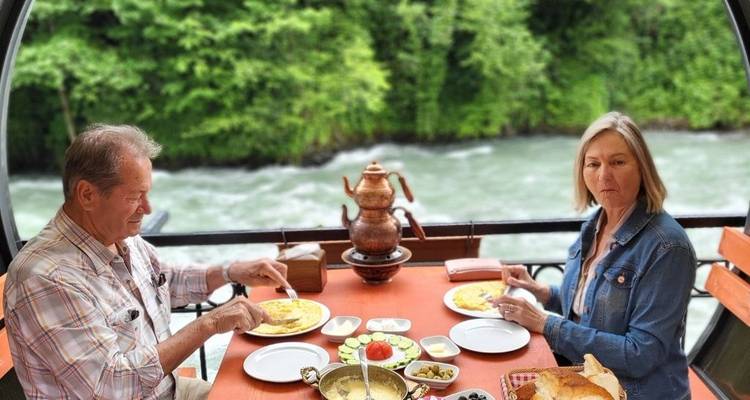 Two people having a meal on a balcony overlooking a river.