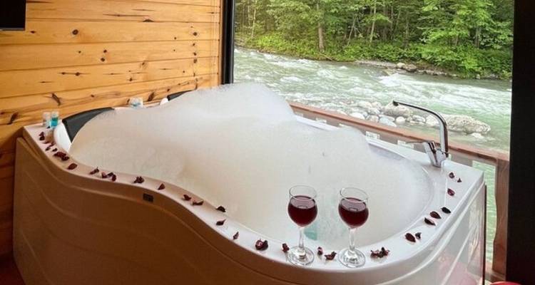 Indoor bathtub with rose petals and river view.