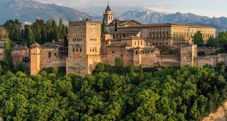 Majestueus uitzicht op het historische Alhambra paleizencomplex omringd door weelderig groen en bergen.