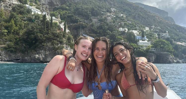 Tres mujeres posando felizmente en un barco con vista panorámica.