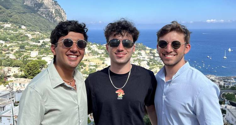 Tres hombres posando con un telón de fondo de vista costera panorámica.