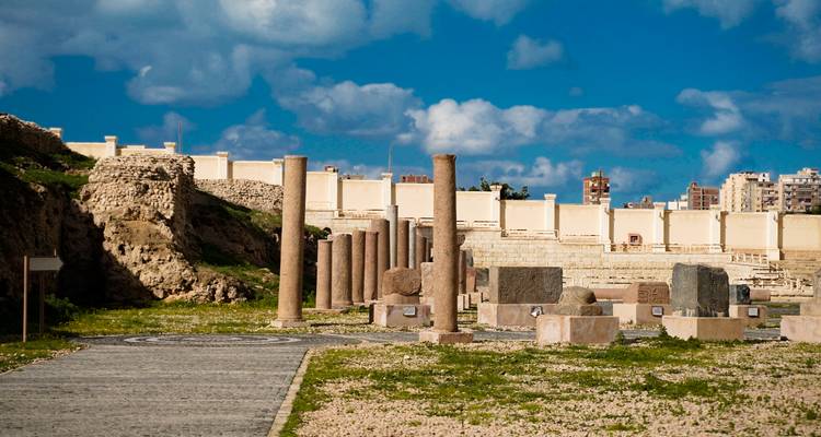 Romeinse ruïnes met zuilen en stenen tegen een blauwe hemel.