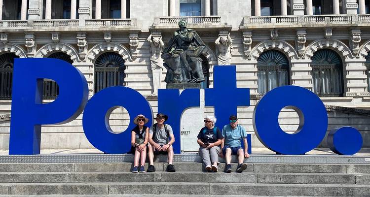 People sitting in front of Porto's large blue city sign.