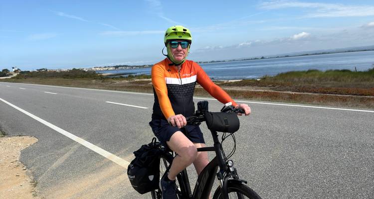 Cyclist on a road near a large body of water.