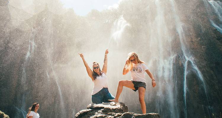 Deux personnes se tenant près d'une grande cascade avec de la brume.