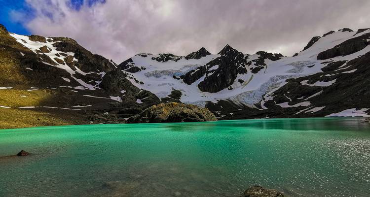 Lac glaciaire turquoise entouré de montagnes enneigées.