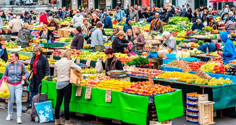 Drukke openluchtproductenmarkt vol met kleurrijke vruchten, groenten en winkelende mensen.