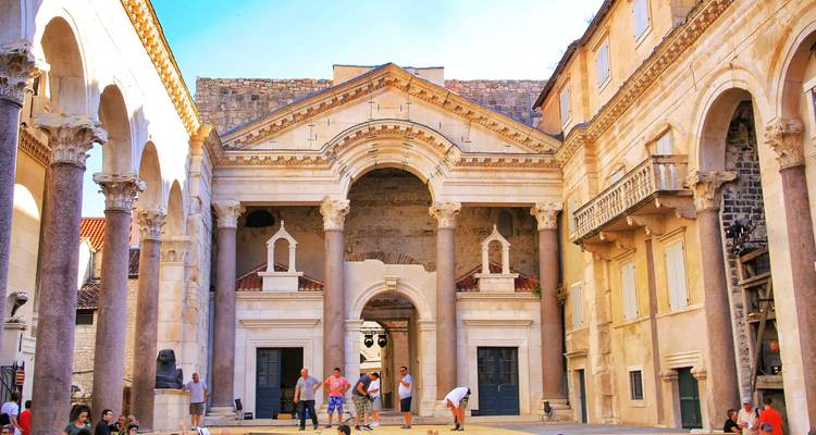 Bezoekers verkennen de Peristyle binnenplaats van het Paleis van Diocletianus, omringd door oude zuilengalerijen.