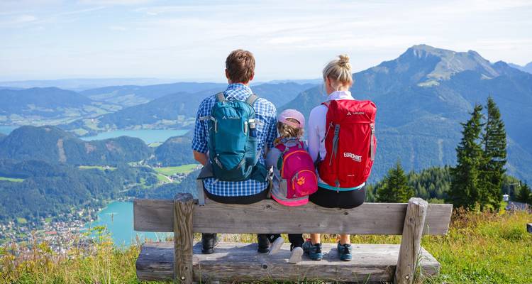 Een familie die op een bank zit met uitzicht op een panoramisch berglandschap.