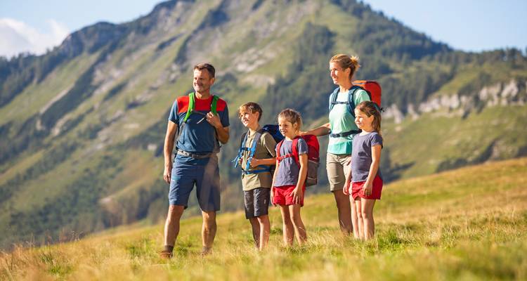 Een familie die uitkijkt over een schilderachtig berglandschap.