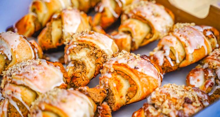 Close-up of freshly baked Polish pastries drizzled with icing and sprinkled with nuts on a tray.