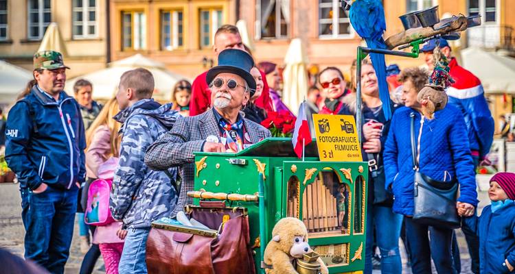 Street performer with a vintage barrel organ entertaining a small crowd in a historic square.