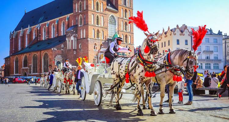 Decorated horse-drawn carriages and drivers waiting beside St. Mary's Basilica in Krakow's main square.